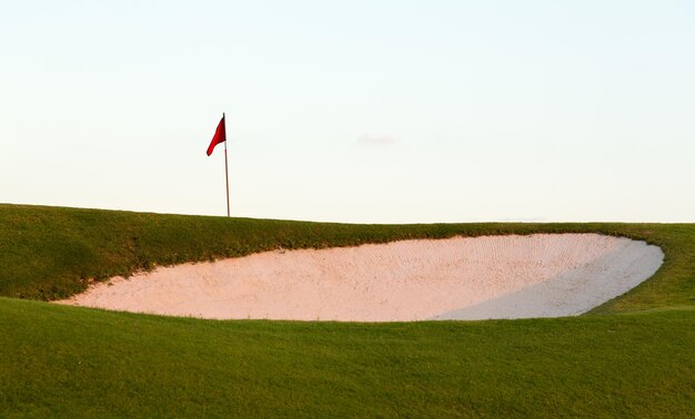 Foto bunker di sabbia davanti al campo da golf e alla bandiera