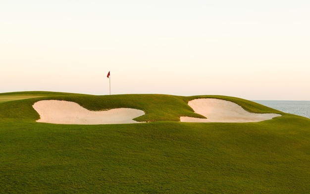 Sand bunker in front of golf green and flag