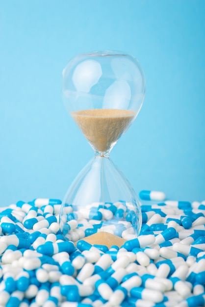 Sand clock on pile of pills