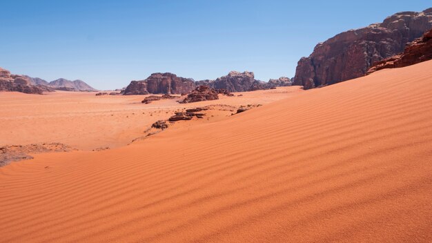 ワディラム砂漠ヨルダンの崖の背景にある砂丘。暑い砂浜の風景。