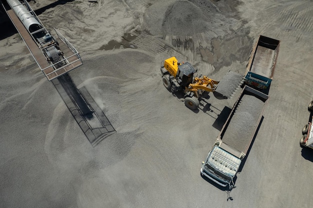 Sand loaders are shoveling rocks into dump trucks