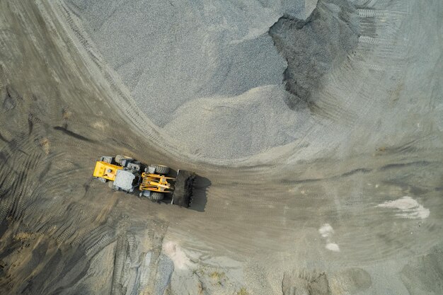 Sand loaders are shoveling rocks into dump trucks