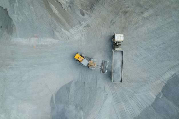 Sand loaders are shoveling rocks into dump trucks