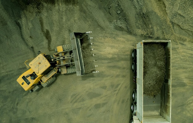 Sand loaders are shoveling rocks into dump trucks