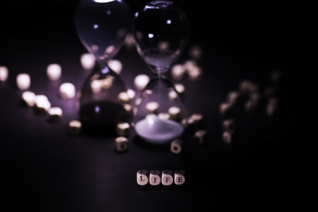 Sand running through the bulbs of an hourglass measuring the passing time in a countdown to a deadline, on a dark table background with copy space.