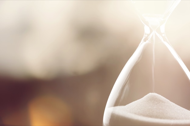 Photo sand running through the bulbs of an hourglass