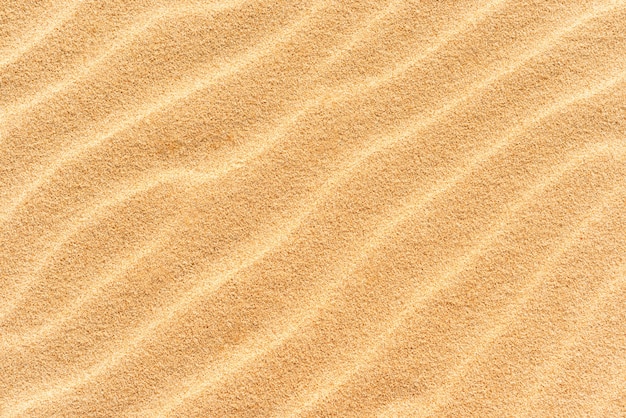 Texture di sabbia sulla spiaggia con onde come sfondo tropicale naturale