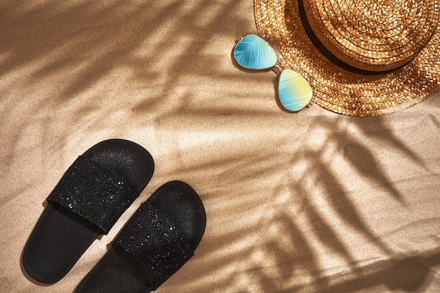 Sandal straw hat and sunglasses on a sandy background