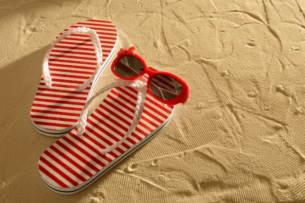 Sandal and sunglasses on a sandy beach, sunset, top view