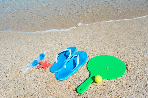 Sandalen, rackets en zeebrillen op een gouden kust