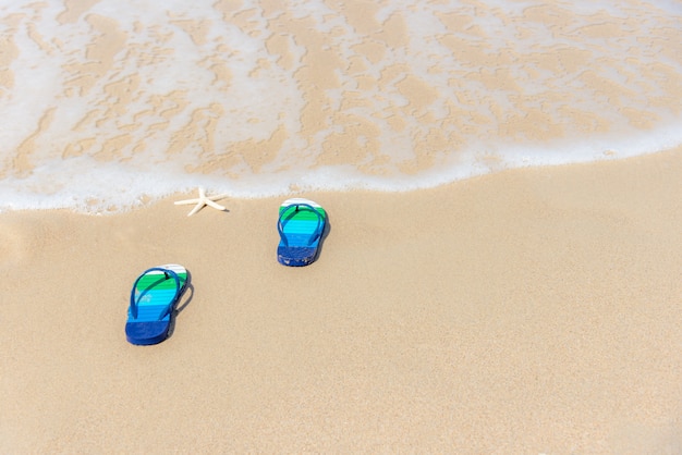 Foto sandali su una spiaggia di sabbia con spruzzi d'acqua dell'oceano, relax e libertà. concetto di vacanze estive.