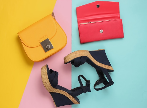 Sandals with platform, yellow leather bag, wallet on colored pastel table