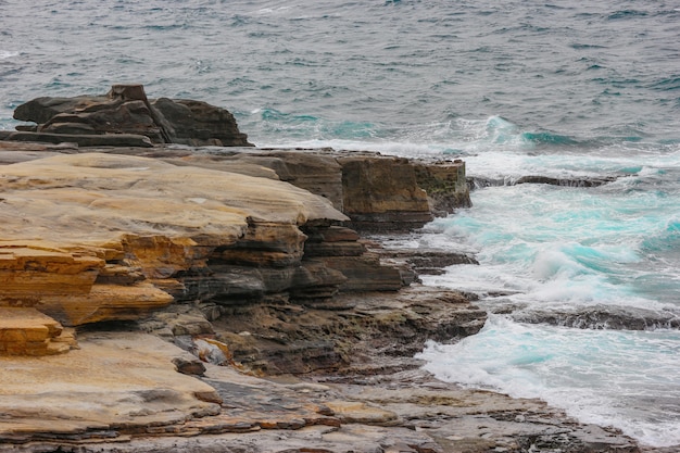 SANDANBEKI stone cliff beach with waving blue sea.