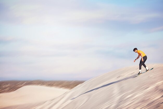 Sandboard desert and mockup with a sports man outdoor on the sand dunes for recreation fun or adventure sky nature and mock up with a male athlete or sandboarding moving downhill at speed