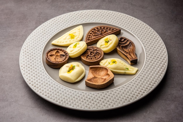 Sandesh or Shondesh sweet food with wooden moulds in a plate