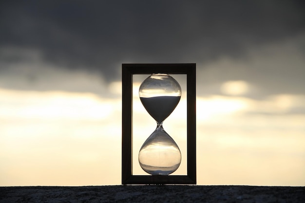 Sandglass on concrete parapet over sky background