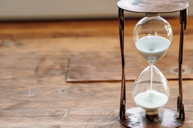 Photo sandglass on wooden bakground close up. time concept