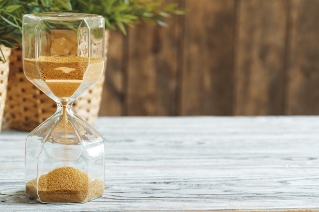 Sandglass sulla fine di legno del bakground in su. concetto di tempo