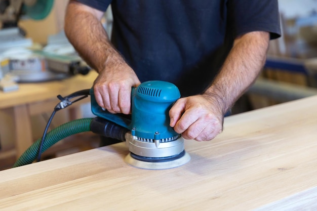 Foto levigatura di una superficie in legno con levigatrice orbitale in officina