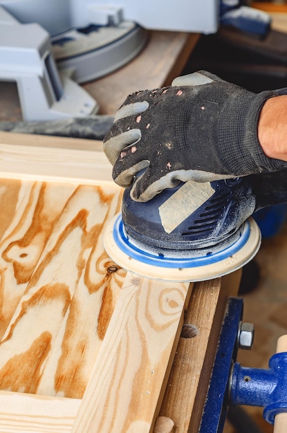 Sanding a wooden board with a handheld electric sander