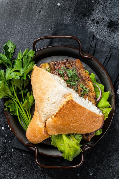 Sandwich balik Ekmek met gegrilde filet van makreel vis tomaten uien en sla Zwarte achtergrond Bovenaanzicht