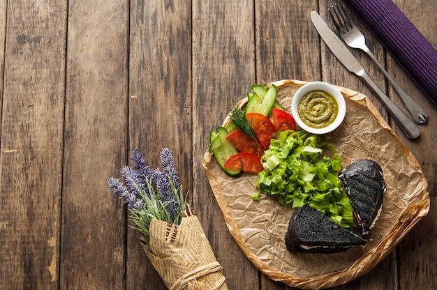 Sandwich of black bread with vegetables on a wooden surface