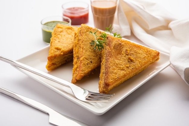 サンドイッチパンパコラまたは三角形のパコラにトマトケチャップ、グリーンチャツネ、人気のインドのティータイムスナックを添えて