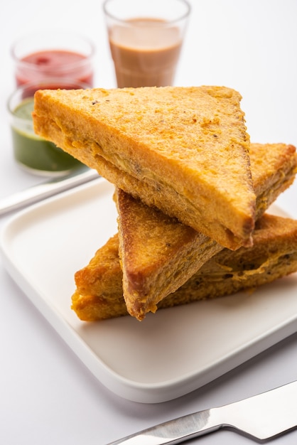 Sandwich bread pakora or triangle shape pakoda served with tomato ketchup, green chutney, popular indian tea-time snack