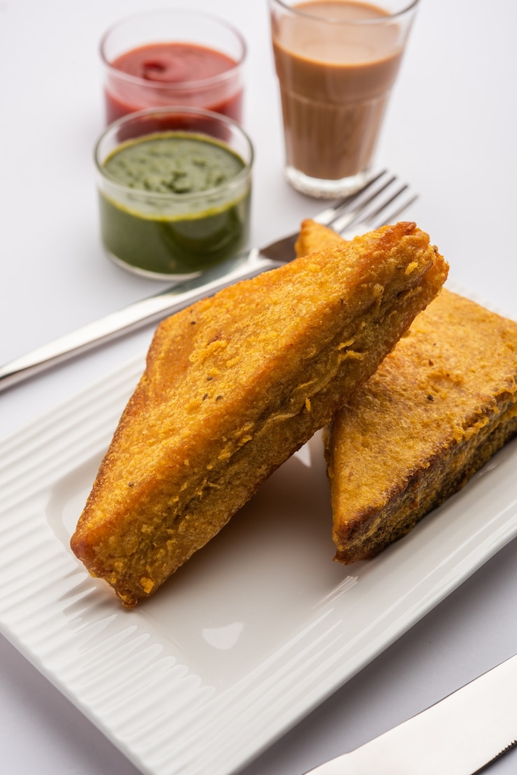 फोटो sandwich bread pakora or triangle shape pakoda served with tomato ketchup, green chutney, popular indian tea-time snack