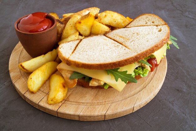 Sandwich en gebakken aardappelen op een houten bord.