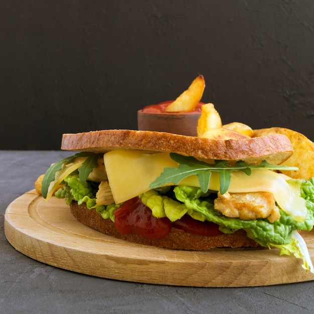 Sandwich and fried potatoes on a wooden Board.