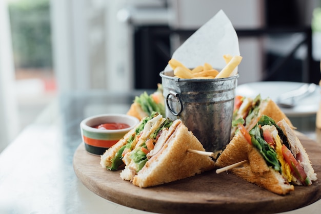 Sandwich and fries on wooden board