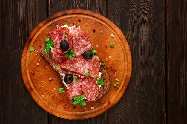 Sandwich grain bread with cream cheese and salami black olives microgreens top view closeup no people Breakfast