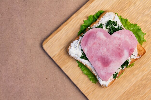 Sandwich made of fried bread, ham, cheese, lettuce in the shape\
of a heart for breakfast