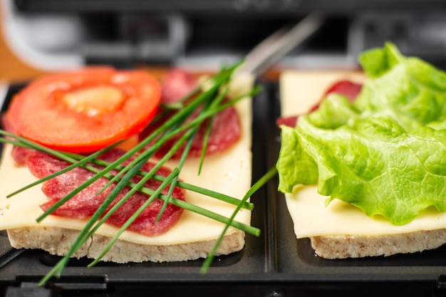 トマト・ハム・オニオン・チーズの2種類のサンドイッチが入ったサンドイッチメーカー 軽食の準備