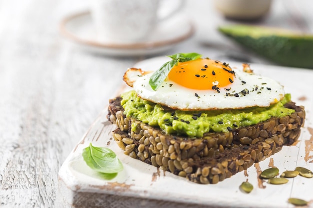 Sandwich met avocado-ei en spinazie op een wit houten achtergrond gezond dieetontbijt