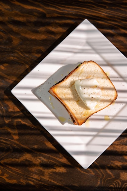 Sandwich met gepocheerd ei en ham geïsoleerd op een houten tafel kopieer ruimte bovenaanzicht