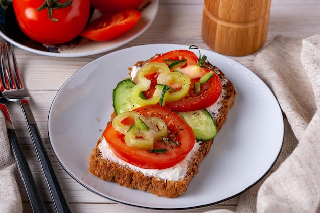 Sandwich met kaas, tomaat, komkommer en peper op een witte plaat