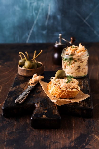 Sandwich met kippenpastei met kappertjes op een donker oud bord.