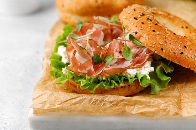 Sandwich met ricotta prosciutto en microgreens bagel met ham als ontbijt op papier