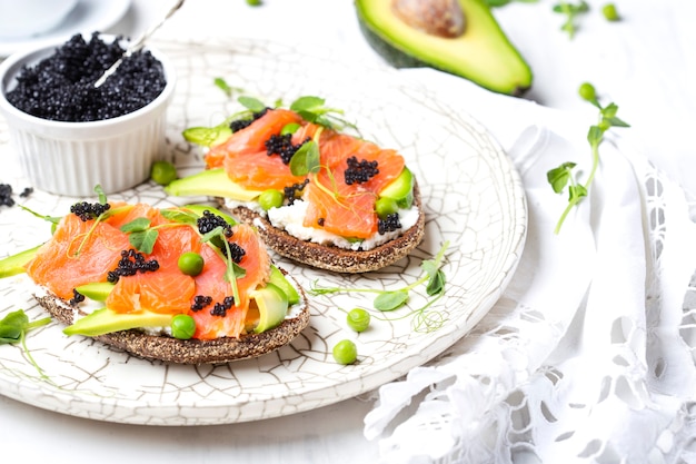 Sandwich met roomkaas, avocado en zalm op een lichte achtergrond