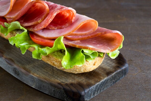 Foto sandwich met salami, ham en salade.