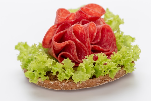 Sandwich met salamiworst op witte achtergrond.