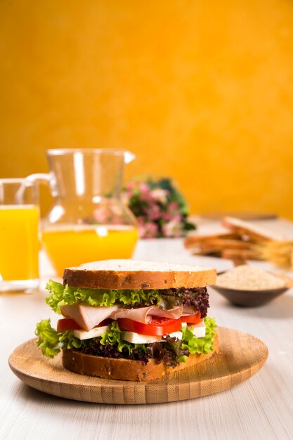 Sandwich op een witte plaat met kalkoenfilet, tomaat, sla en kaas op tafel