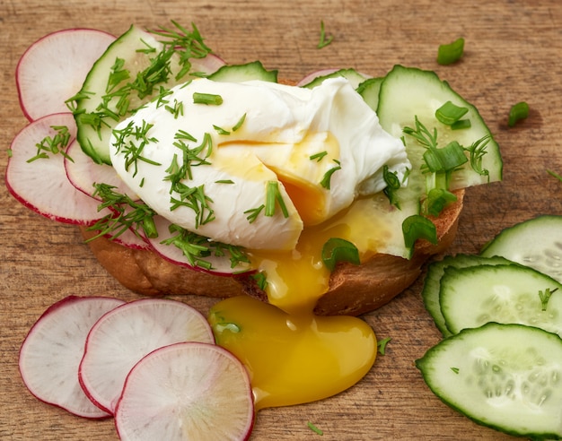 Sandwich op geroosterde witte sneetje brood met gepocheerde eieren, groene bladeren van ui, ochtend ontbijt