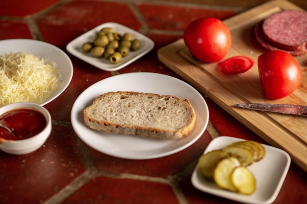 Sandwich preparation A piece of bread on a plate surrounded by various ingredients