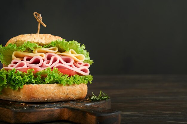 Sandwich Tasty sandwich with ham or bacon cheese tomatoes lettuce and grain bread on dark backgrounds Delicious club sandwich or school lunch breakfast or snack