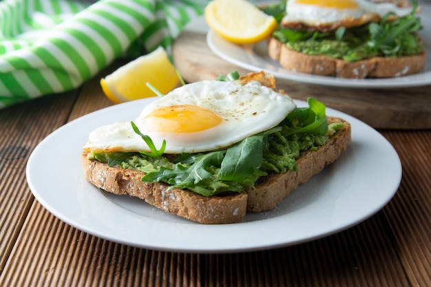 Sandwich toast with avocado and a fried egg on wood table. Healthy food. 