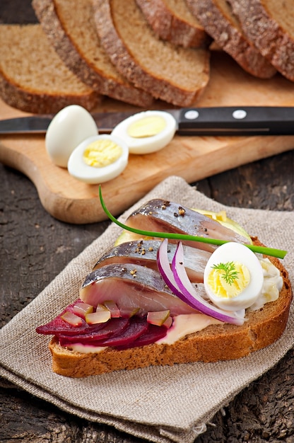 Sandwich van roggebrood met haring, bieten, uien en ei