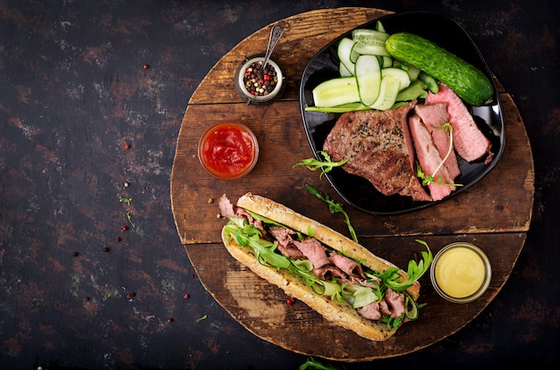 Sandwich of whole wheat bread with roast beef, cucumber and arugula. .